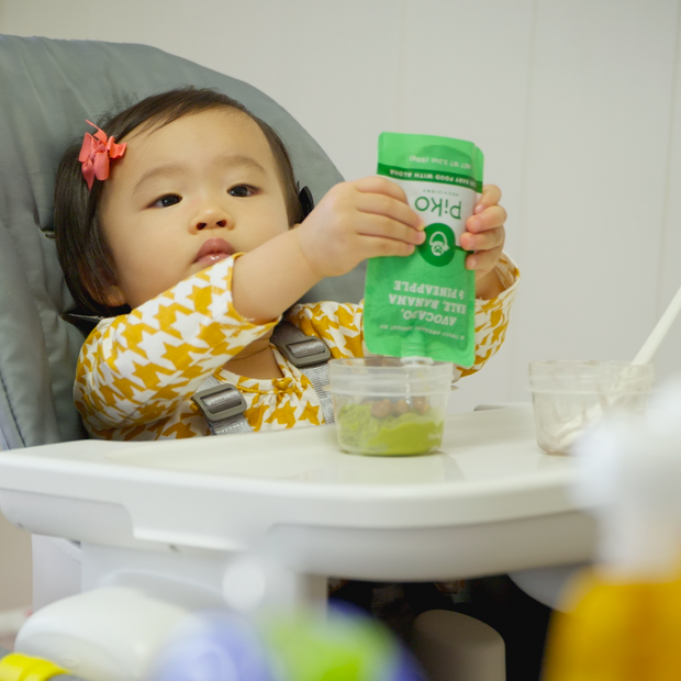 Baby in a high chair eating a Piko pouch